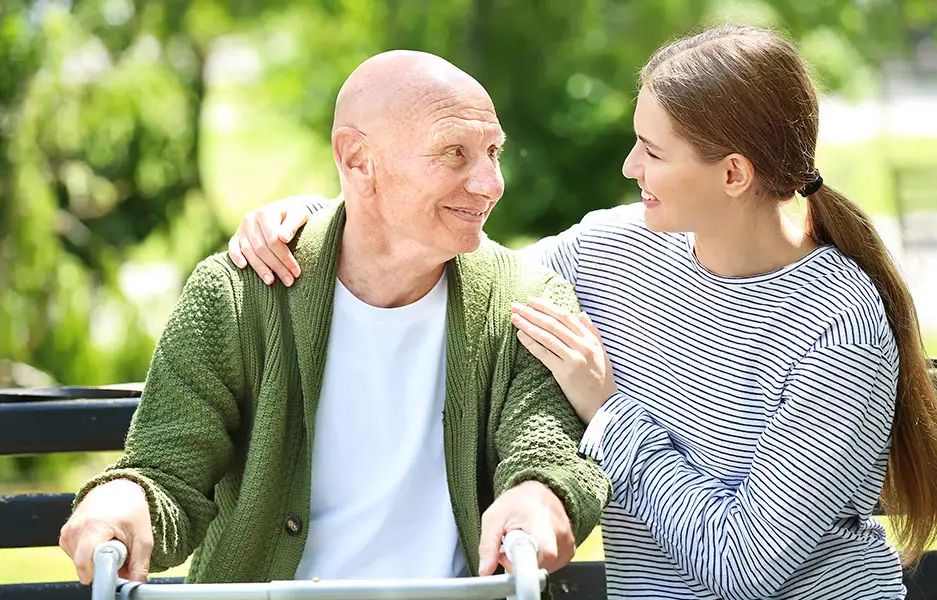a young woman comforting an older man on a zimmer frame
